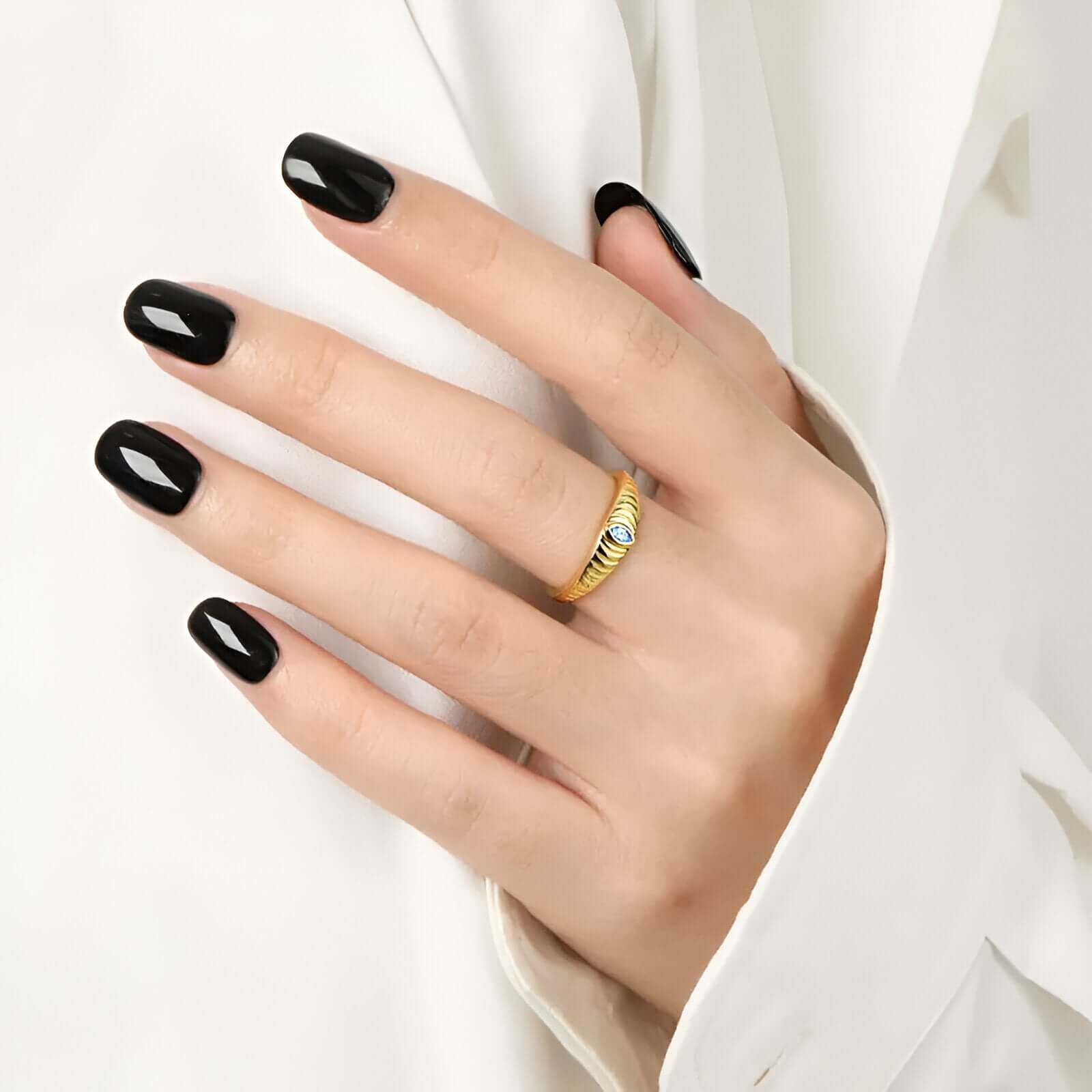 model wearing the Iridian Band featuring marquise blue zircon on a 18k gold etched band.