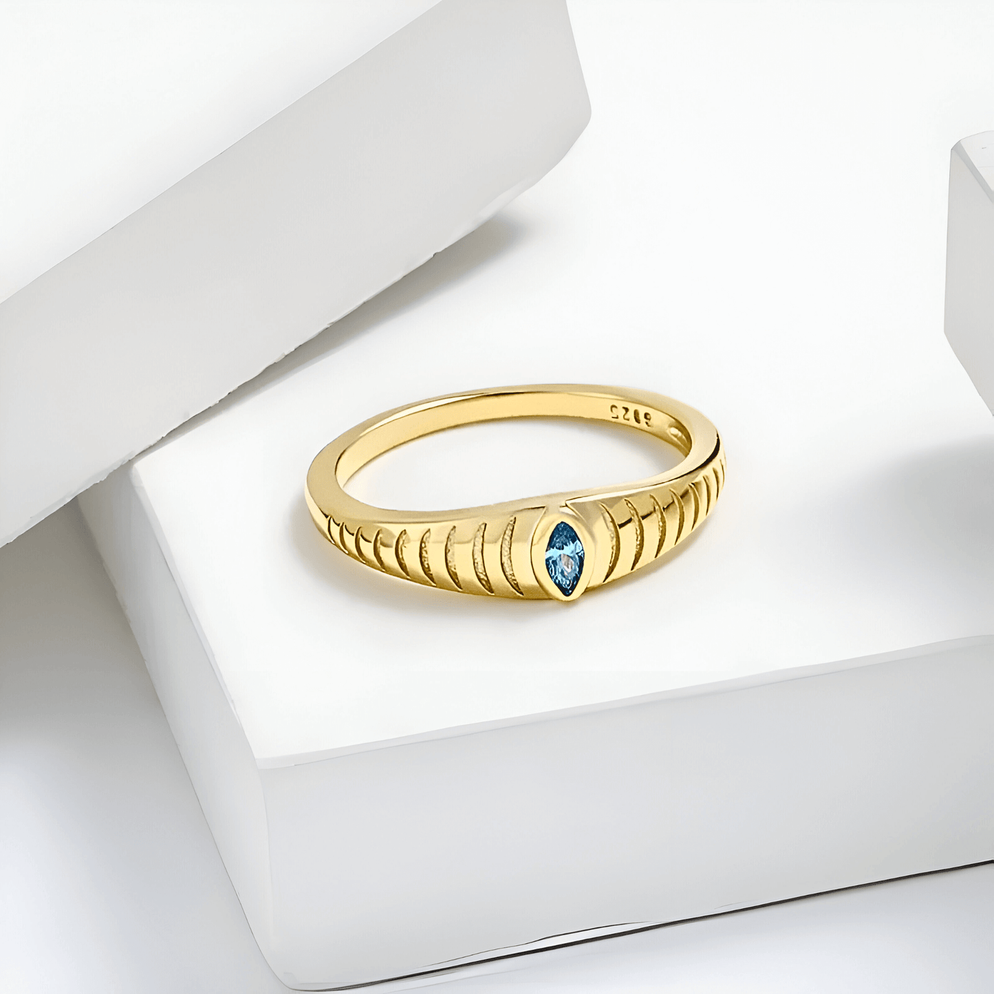 Iridian Band featuring a blue zircon in 18k gold, with an etched marquise cut design on a sleek band.