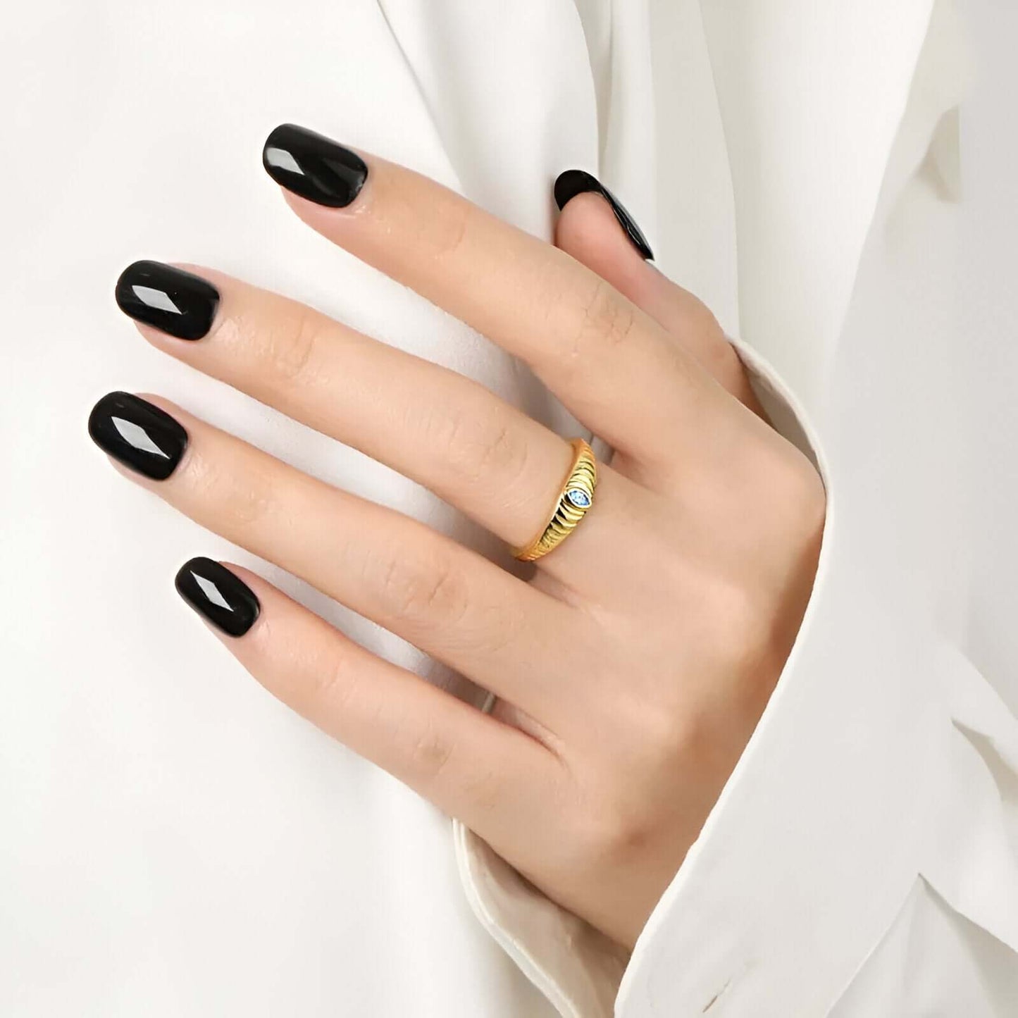 model wearing the Iridian Band featuring marquise blue zircon on a 18k gold etched band.